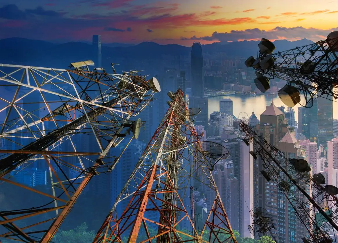 Communication towers overlooking city skyline at sunset